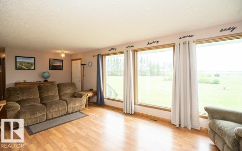 Expansive living area with large windows, wood-finish flooring, and light-colored walls - 57532 Rg Rd 270, Rural Westlock County, AB 