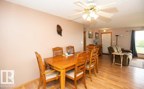 Open-concept living area featuring wood-finish flooring, a ceiling fan with integrated lighting, and a large window providing outdoor scenery - 57532 Rg Rd 270, Rural Westlock County, AB 