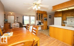 Open-concept living area featuring a dining space with wood-finish flooring, an adjacent kitchen, and a living area with large windows - 