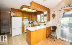 Kitchen featuring wood-finish cabinetry, white countertops, a white refrigerator, a white range, and a dual-basin stainless steel sink - 