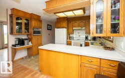 Kitchen featuring wood-finish cabinetry, white appliances, and a central island with white countertops - 
