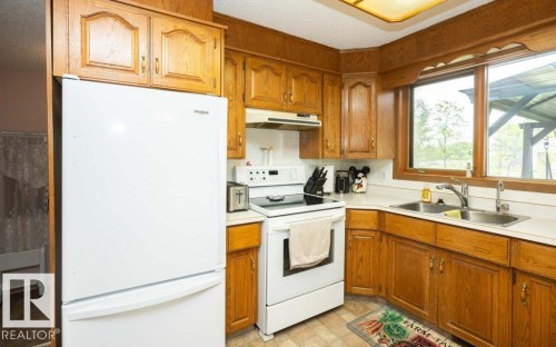 Kitchen featuring wood-finish cabinetry, white appliances, and a double basin stainless steel sink - 57532 Rg Rd 270, Rural Westlock County, AB 