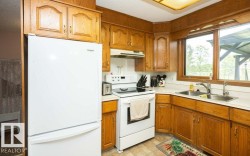 Kitchen featuring wood-finish cabinetry, white appliances, and a double basin stainless steel sink - 