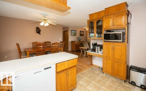 Kitchen featuring wood cabinetry, a built-in microwave, and a white dishwasher - 57532 Rg Rd 270, Rural Westlock County, AB 