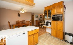 Kitchen featuring wood cabinetry, a built-in microwave, and a white dishwasher - 