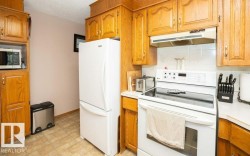 Kitchen featuring wood cabinetry, white appliances, tile backsplash, and linoleum flooring - 