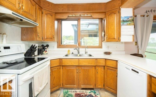 Kitchen featuring wood cabinetry, a double basin sink, white countertops, a built-in dishwasher, and a window - 57532 Rg Rd 270, Rural Westlock County, AB 
