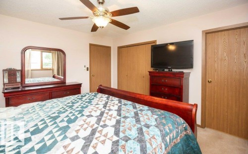Bedroom featuring a ceiling fan with integrated lighting, wood-finish bi-fold closet doors, a single window, and light-toned wall-to-wall carpeting - 57532 Rg Rd 270, Rural Westlock County, AB 