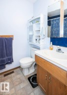 Bathroom featuring a wood-finish vanity with an integrated sink, a white toilet, and tile flooring - 