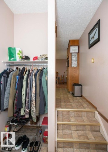 Lower-level area featuring a built-in closet with shelving, a staircase with wood-finish risers, and a hallway with patterned flooring - 57532 Rg Rd 270, Rural Westlock County, AB 