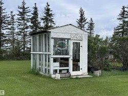 Freestanding greenhouse structure with paneled glass sections and a white paneled door - 