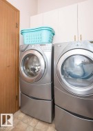 Dedicated laundry area featuring white upper cabinetry, a light wood-finish door, and patterned tile flooring - 