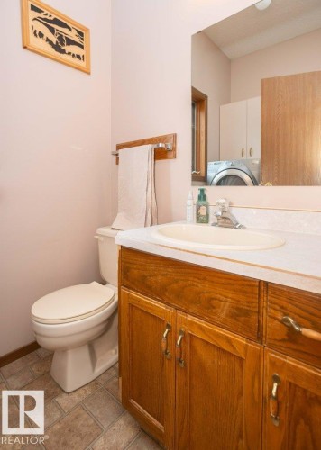 Bathroom vanity featuring a wood-finish cabinet, integrated sink, and a framed mirror - 57532 Rg Rd 270, Rural Westlock County, AB 