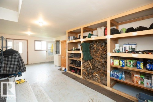 Utility space featuring built-in wood shelving, a concrete floor, and multiple entryways - 57532 Rg Rd 270, Rural Westlock County, AB 