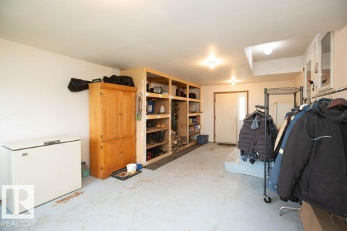 Utility room with built-in wooden shelving, a light-colored entry door, overhead lighting, and built-in white cabinetry - 57532 Rg Rd 270, Rural Westlock County, AB 