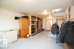 Utility room with built-in wooden shelving, a light-colored entry door, overhead lighting, and built-in white cabinetry - 