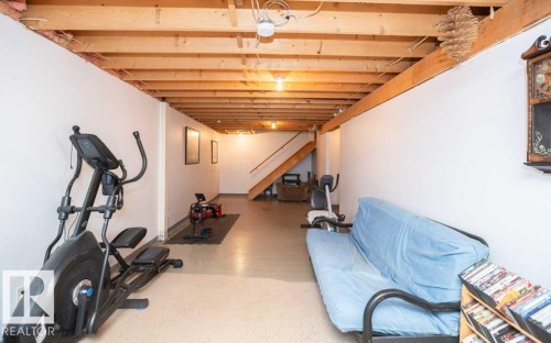 Finished lower level with exposed ceiling joists, concrete flooring, white painted walls, and wood stairs - 57532 Rg Rd 270, Rural Westlock County, AB 