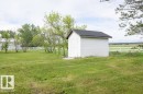 White exterior storage shed with a dark shingle roof, positioned on a grassy lawn - 57532 Rg Rd 270, Rural Westlock County, AB 