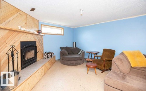 Wood-paneled fireplace with a hearth featuring a cast-iron stove insert - 57532 Rg Rd 270, Rural Westlock County, AB 