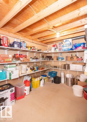 Utility room featuring extensive built-in shelving, exposed wood ceiling joists, plywood ceiling decking, and concrete flooring - 57532 Rg Rd 270, Rural Westlock County, AB 