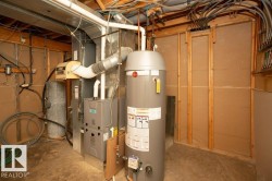 Utility space featuring a water heater, furnace, and exposed overhead ductwork - 