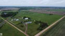 Expansive acreage featuring a white residence, multiple outbuildings, and extensive green fields - 