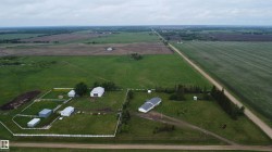 Expansive property featuring a white ranch-style residence, multiple outbuildings, and a large fenced area - 