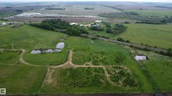 Expansive acreage featuring multiple ponds, established tree lines, open green fields, and a distant treed area - 