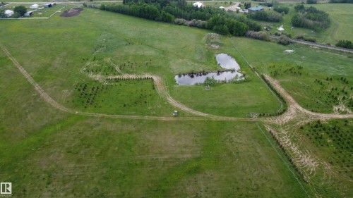 Expansive green acreage featuring a natural pond, established treelines, and visible vehicle paths - 57532 Rg Rd 270, Rural Westlock County, AB 