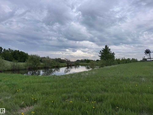 Expansive green space featuring a tranquil pond with reflective waters and surrounding foliage - 57532 Rg Rd 270, Rural Westlock County, AB 