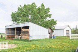 Open-sided pole barn with a corrugated metal roof and siding, featuring exposed wooden posts - 