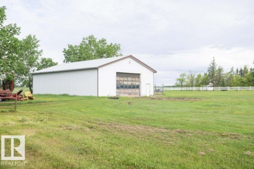 White metal outbuilding with a roll-up garage door and an additional pedestrian door - 57532 Rg Rd 270, Rural Westlock County, AB 