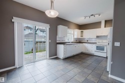 Kitchen and dining area featuring white cabinetry and appliances, tile flooring, track lighting, and a suspended ceiling light - 