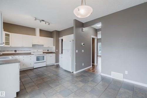 Kitchen with white cabinetry, tile flooring, and a white appliance suite including a range, refrigerator, and dishwasher - 38 1780 Glastonbury Boulevard, Edmonton, AB 