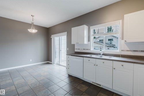 Kitchen featuring white cabinetry, a double basin sink, and a tiled backsplash - 38 1780 Glastonbury Boulevard, Edmonton, AB 