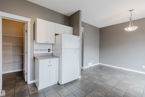 Kitchen area featuring white cabinetry, a white refrigerator, and a light-toned countertop - 38 1780 Glastonbury Boulevard, Edmonton, AB 