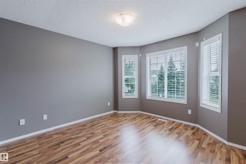 Room featuring wood-finish flooring, neutral gray walls, white baseboards, and a semi-flush mount ceiling light - 38 1780 Glastonbury Boulevard, Edmonton, AB 