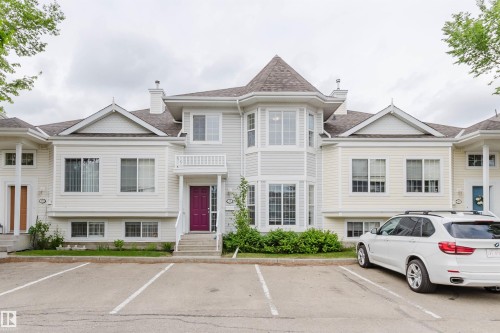 Multi-level townhouse exterior featuring light-colored siding, a prominent turret with multiple windows, and a vibrant purple entry door with white railings - 38 1780 Glastonbury Boulevard, Edmonton, AB 