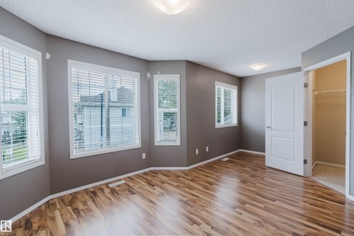 Spacious room with wood-finish flooring and multiple windows featuring white blinds - 38 1780 Glastonbury Boulevard, Edmonton, AB 