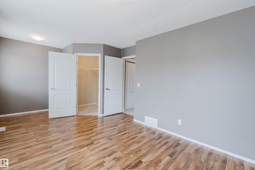 Spacious interior room featuring wood-finish flooring, neutral gray wall tones, white trim, and a semi-flush ceiling light fixture - 38 1780 Glastonbury Boulevard, Edmonton, AB 