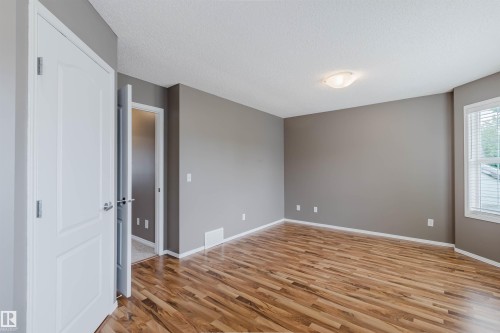 Spacious room featuring wood-finish flooring, neutral gray walls, and white trim - 38 1780 Glastonbury Boulevard, Edmonton, AB 