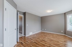 Spacious room featuring wood-finish flooring, neutral gray walls, and white trim - 
