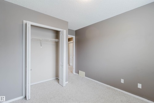 Carpeted room with a bi-fold door closet featuring a wire shelf and hanging rod - 38 1780 Glastonbury Boulevard, Edmonton, AB 