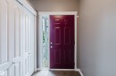 Panel door with sidelight entry, featuring a deep red finish - 38 1780 Glastonbury Boulevard, Edmonton, AB 