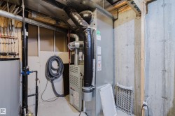 Utility room featuring a forced-air furnace, exposed ductwork, concrete foundation walls, and a hot water heater - 