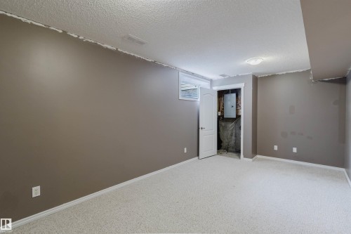 Spacious room featuring light-colored carpet flooring, neutral-toned walls, a white ceiling, and a single ceiling-mounted light fixture - 38 1780 Glastonbury Boulevard, Edmonton, AB 