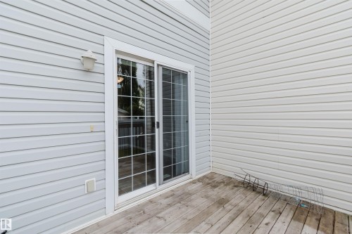 Sliding glass door with grid panes, wood deck, and light-colored horizontal siding - 38 1780 Glastonbury Boulevard, Edmonton, AB 