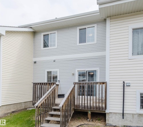 Rear exterior featuring a multi-level wood deck with stairs to ground level, light-colored horizontal siding, and multiple windows - 38 1780 Glastonbury Boulevard, Edmonton, AB 