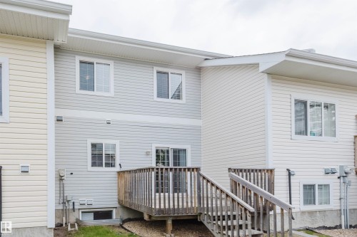 Exterior deck with wooden railings and steps, featuring multiple windows and sliding glass doors - 38 1780 Glastonbury Boulevard, Edmonton, AB 