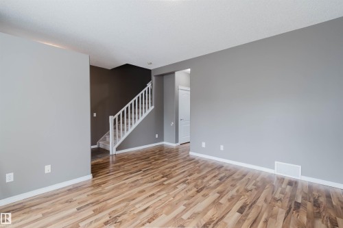 Spacious room featuring wood-finish flooring, light grey walls, and white baseboards - 38 1780 Glastonbury Boulevard, Edmonton, AB 